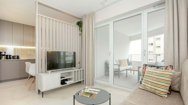 A modern living room with a TV, sofa, and a small coffee table.