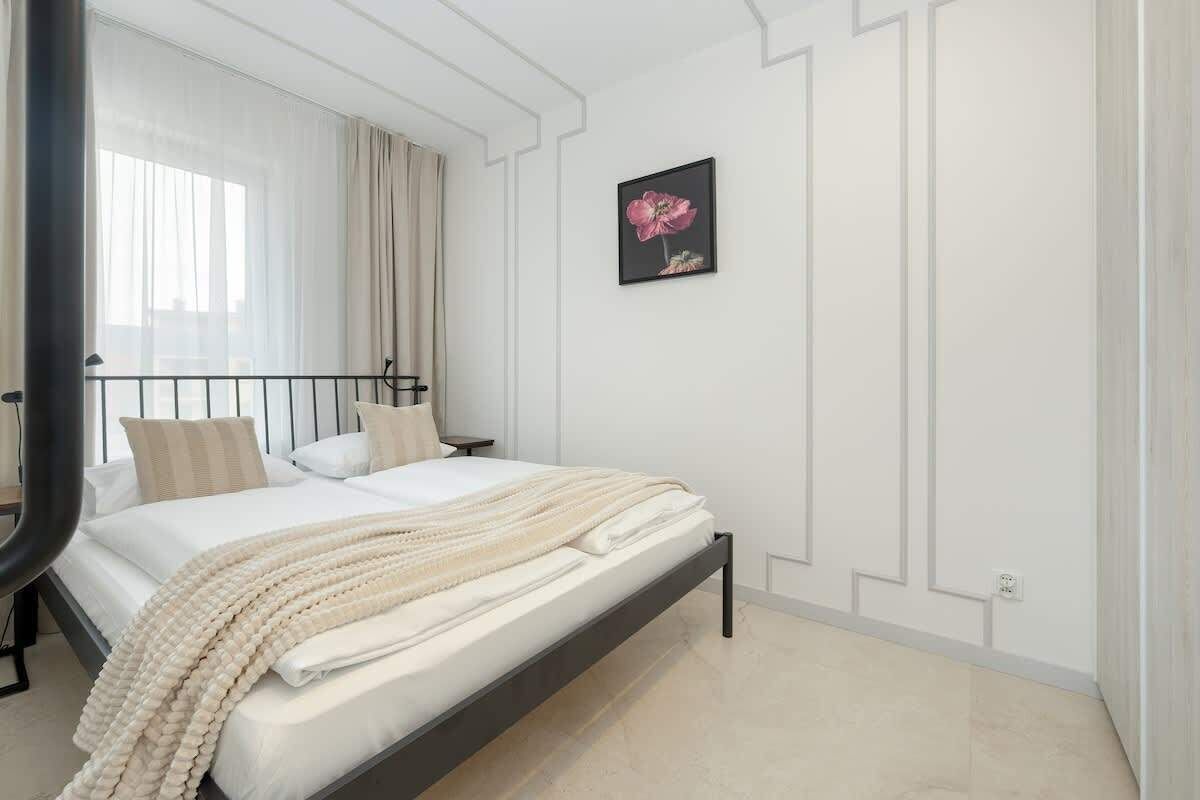 Ein modernes Schlafzimmer mit einem Bett, einem Nachttisch, einem Wandbild und einem Fenster mit Vorhängen.