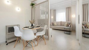 A modern living room with a sofa, a dining table with chairs, and a white partition.