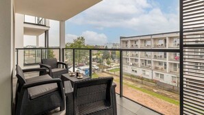 A balcony with wicker furniture and a view of neighboring buildings.