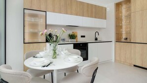 A modern kitchen with white cabinets, a wooden countertop, and a dining area with a white table set for four.