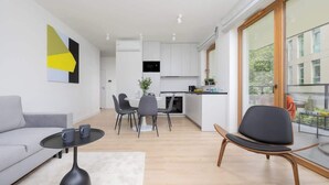 Un salon moderne avec un canapé gris, une table basse noire et un coin repas comprenant une table et des chaises blanches.
