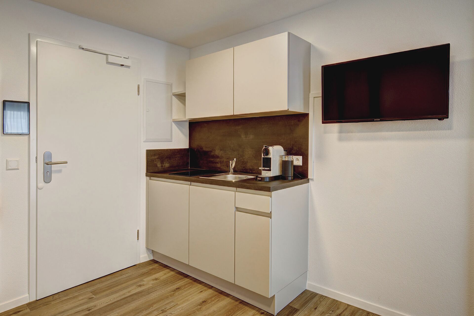 A compact kitchen with white cabinets, a wooden countertop, and a built-in oven.