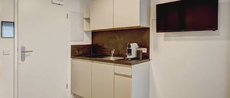 A compact kitchen with white cabinets, a wooden countertop, and a built-in oven.