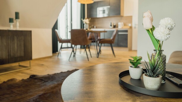 Un soggiorno moderno con pavimento in legno, un tavolino rotondo e un'area pranzo sullo sfondo.