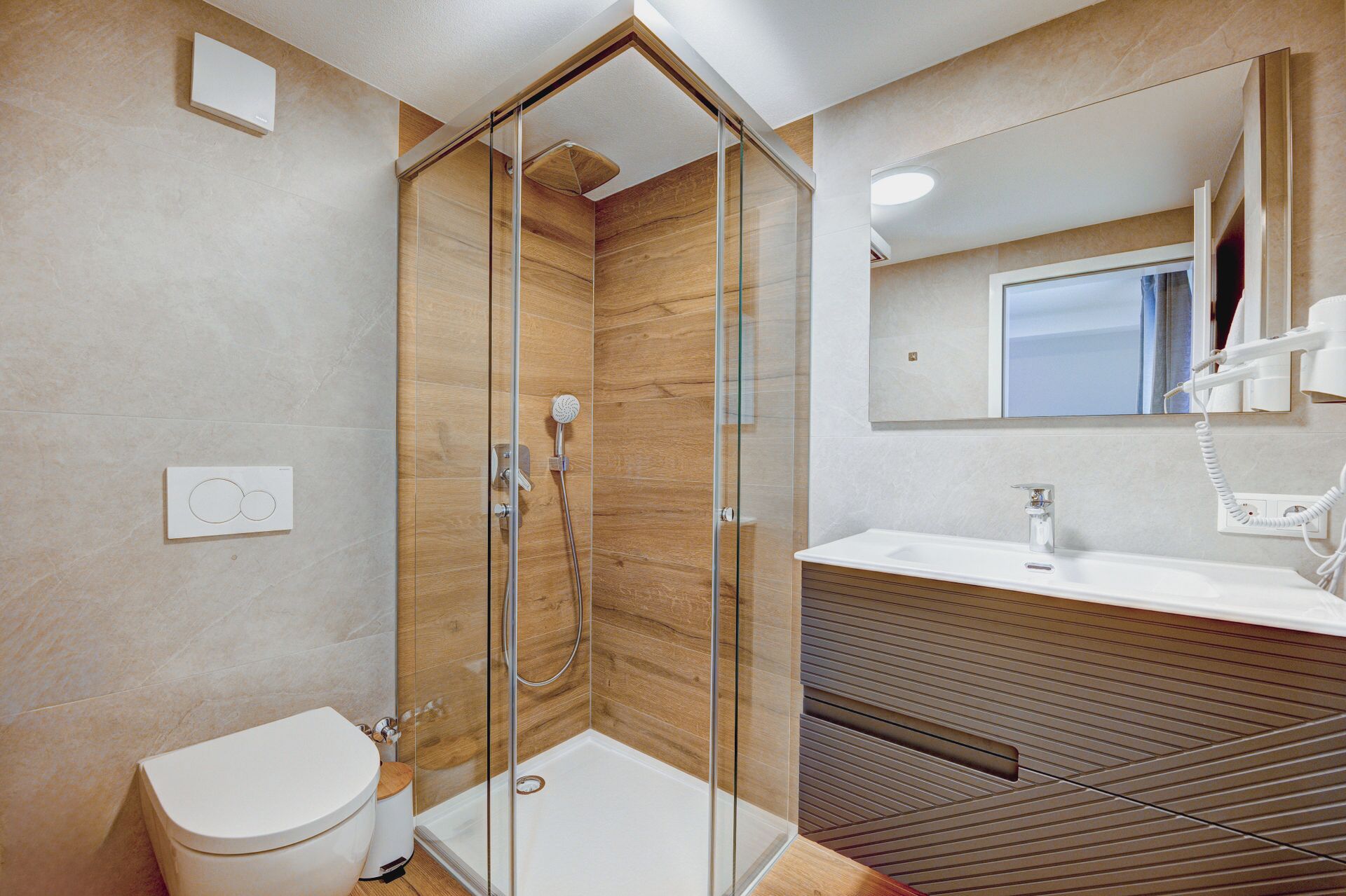 A modern bathroom with a glass-enclosed shower, a toilet, a sink, and a mirror.