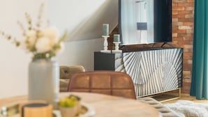 Un soggiorno moderno con televisione montata su una parete in mattoni, un mobile decorato e un'area pranzo con tavolo e sedie.