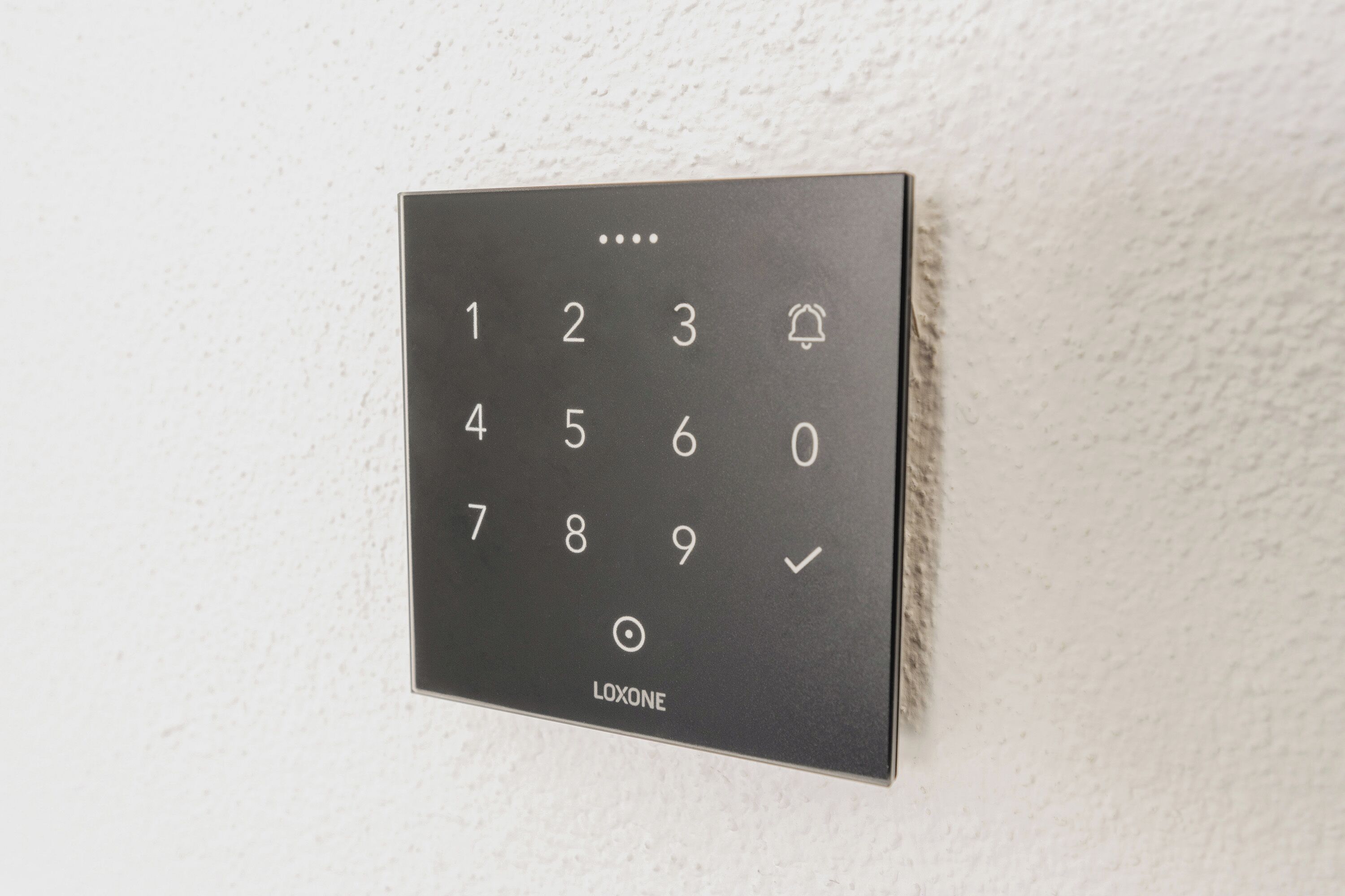 Un teclado Loxone en una pared con textura.