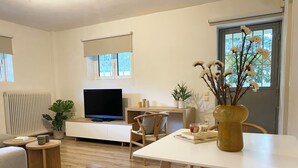 Un salon moderne avec un téléviseur à écran plat, des meubles en bois, une table à manger et une plante en pot.