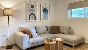 Un salon moderne avec un canapé gris, deux tables d’appoint et un lampadaire.
