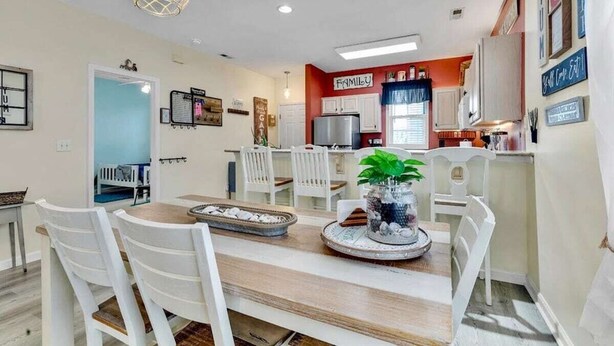 Un coin repas avec une table en bois, des chaises blanches et un élément décoratif au centre.