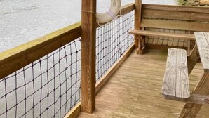 Eine Holzterrasse mit einem Rettungsring, der an einem Pfahl hängt, mit Blick auf einen Fluss.