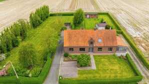 Ein ländliches Haus mit Ziegeldach, umgeben von gepflegten Rasenflächen und Feldern.