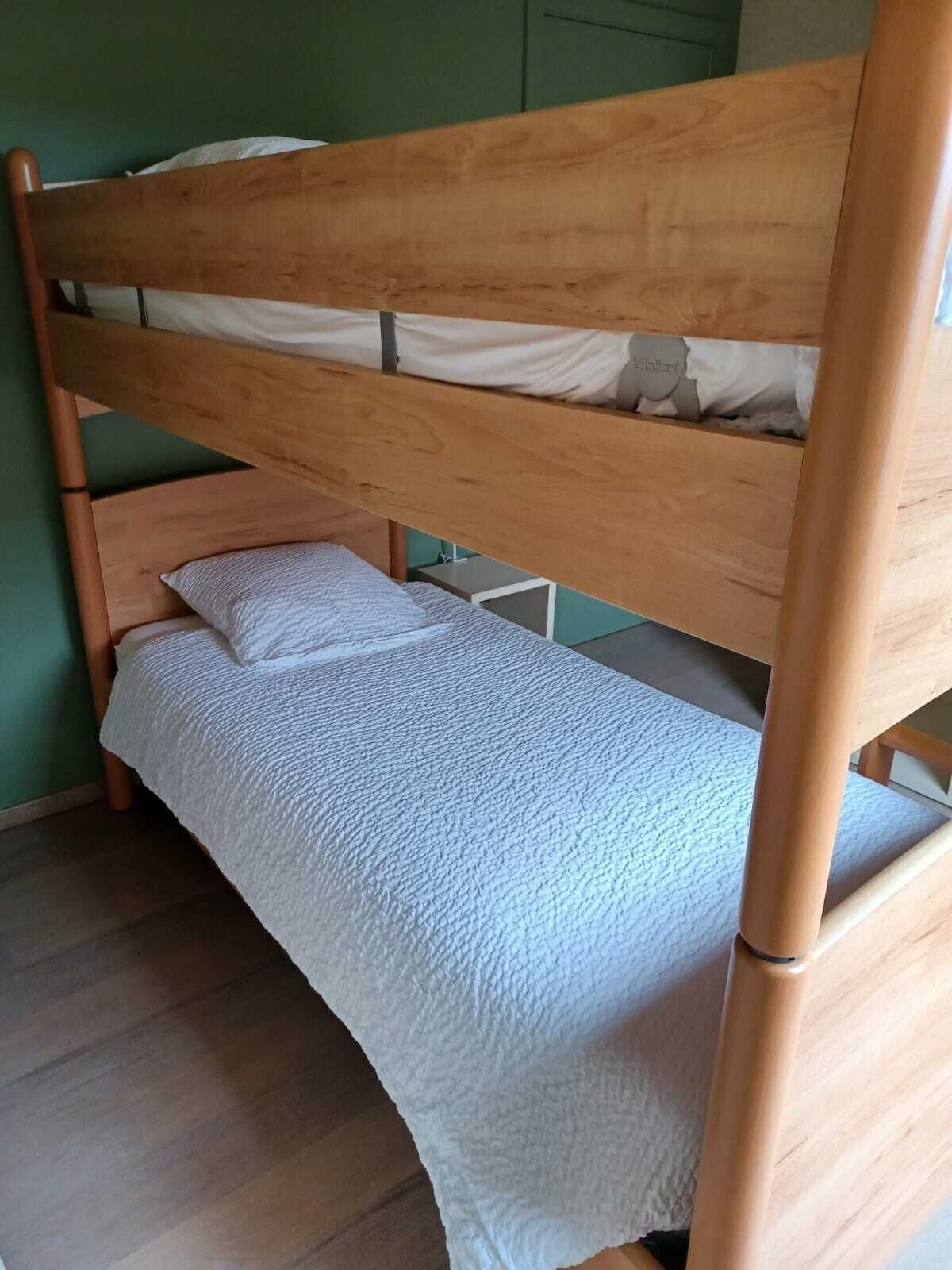 Un lit superposé avec un matelas blanc et un lit inférieur recouvert d’une couette blanche.