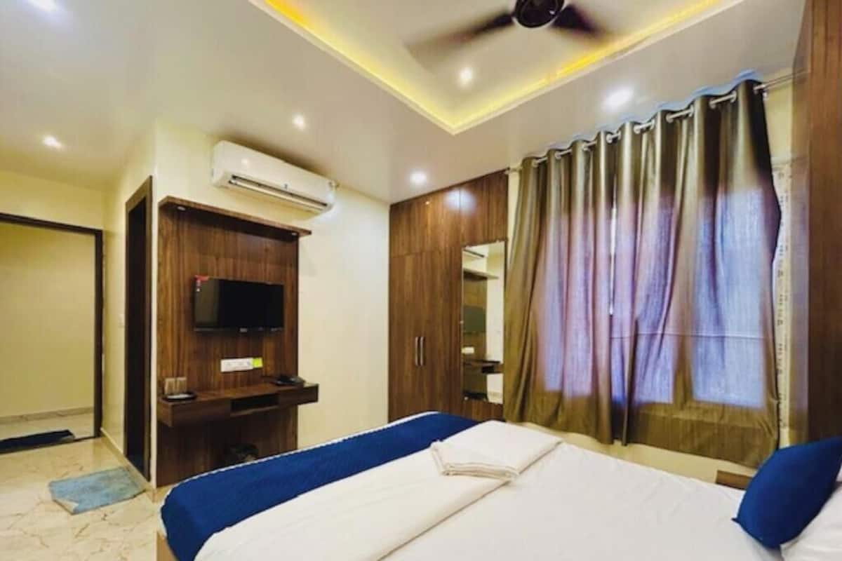 Habitació d'hotel amb un llit, televisió, aire condicionat i ventilador de sostre.
