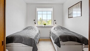 Ein Zimmer mit zwei Betten, einem Fenster mit Blick und einem gerahmten Bild an der Wand.