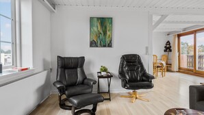 Ein modernes Wohnzimmer mit zwei schwarzen Ledersesseln, einem Holztisch und einem Bild an der Wand.