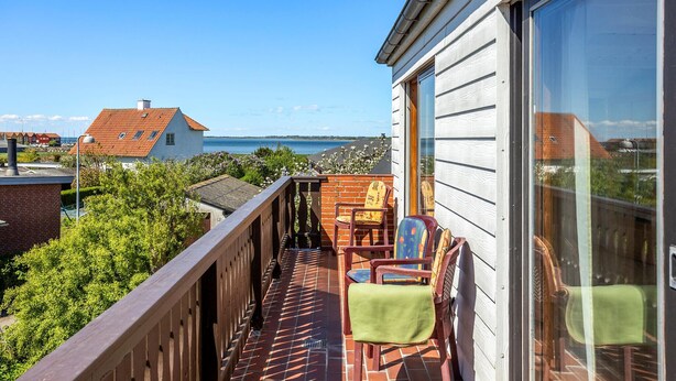 Ein Balkon mit Blick auf das Meer, eine Ziegelmauer und ein Holgitter.