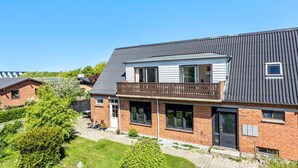 Ein zweistöckiges Haus mit Balkon, Ziegelaußenwand und Metalldach.