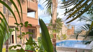 Une vue sur la piscine, avec une végétation tropicale luxuriante et un bâtiment en arrière-plan.