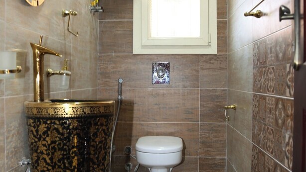 A bathroom with a gold and black sink, a white toilet, and a shower. - Spacious 6-bedroom mansion in enjoyable 6th of October City with WiFi, AC (Giza)