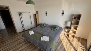 Un dormitorio ordenado con cama, mesitas de noche, estantería y una escalera.