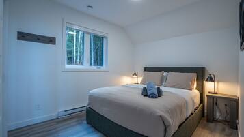Un dormitorio con cama, lámparas de noche, una ventana y suelo de madera.