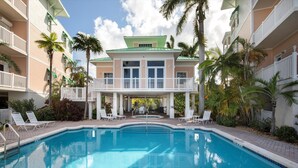 Un hôtel doté d’une piscine, de balcons blancs et de palmiers.