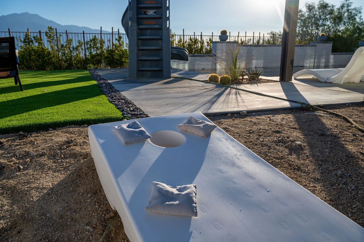A flat surface with a hole in the center, surrounded by a paved area with a metal fence, a ladder, and a slide.
