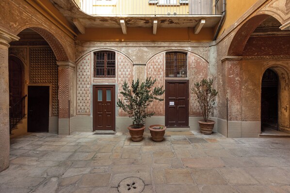 An interior courtyard with stone flooring, wooden doors, and potted plants.