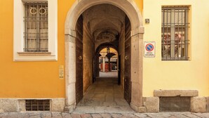 Un passage en arc surmonté d’un panneau indiquant « interdiction de stationner », qui mène à l’entrée d’un immeuble.
