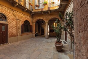 An interior courtyard with stone flooring, arched doorways, and potted plants.