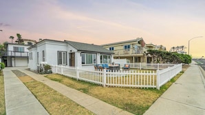 A residential neighborhood with houses, a white picket fence, and a grassy lawn.