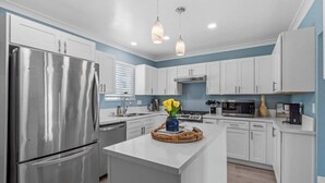 A modern kitchen with white cabinetry, stainless steel appliances, and a central island.