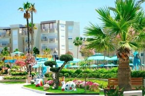 A modern hotel with multiple floors, outdoor seating, and lush landscaping. - Cozy 2-bedroom apartment with big pools perfect for family summer escape! (Monastir)