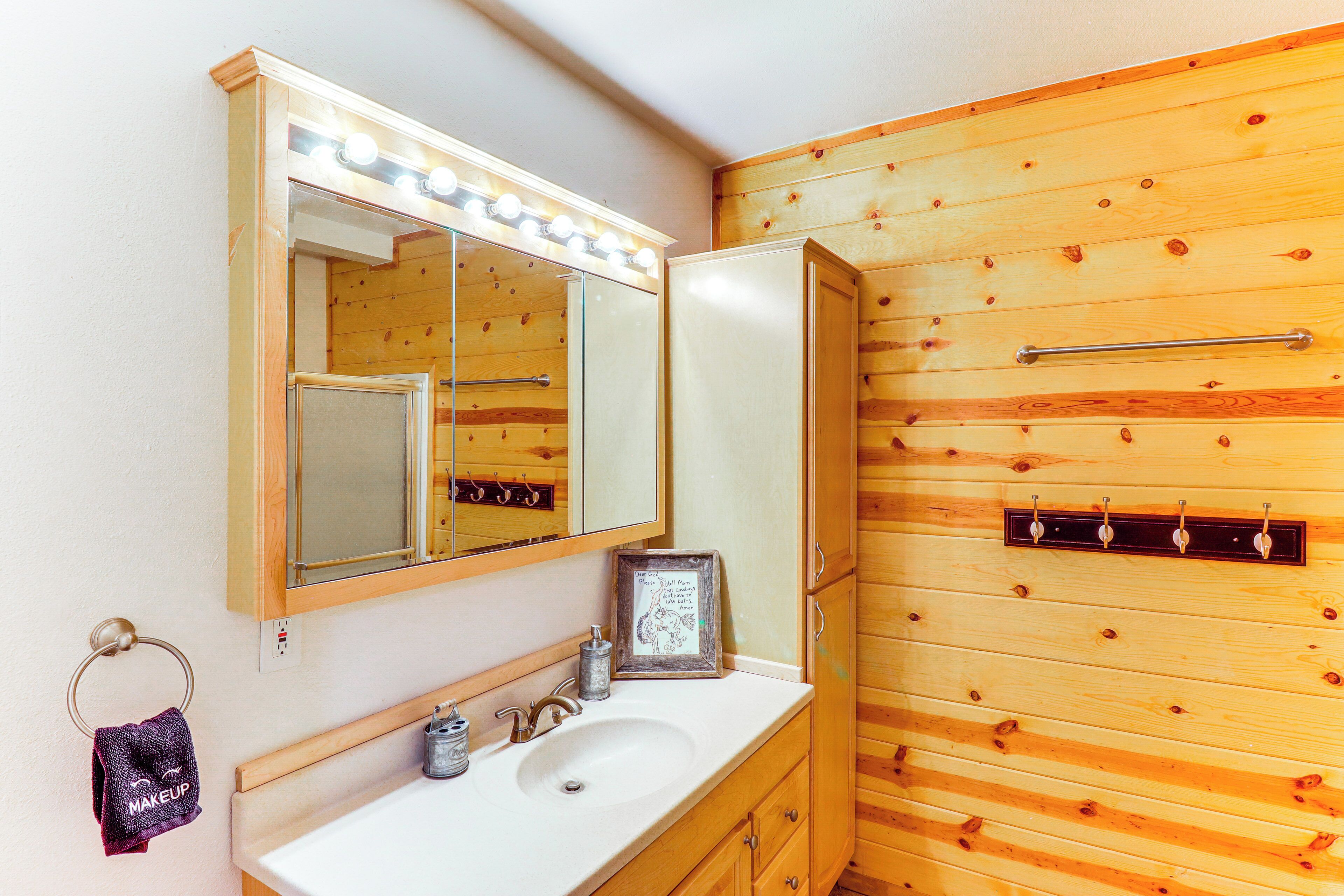 Une salle de bain avec un mur en bois, un lavabo avec un miroir et un porte-serviettes.