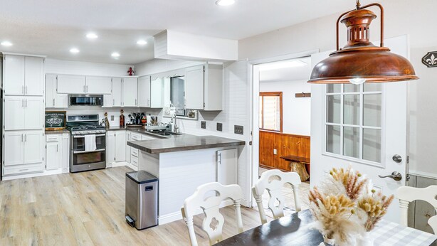 A modern kitchen with white cabinets, a stainless steel refrigerator, and a dining area with a checkered tablecloth and white chairs.