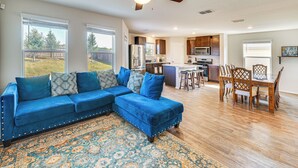 A spacious living area with a blue sectional sofa, a patterned rug, and a dining area with wooden chairs and a table. - San Antonio Home w/ Pool Access: 11 Mi to Seaworld (San Antonio)