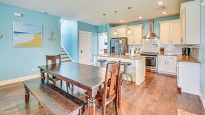 A spacious kitchen with a wooden dining table, white cabinets, and a view of the beach through the window. - Close to Beaches: Palm Coast Home w/ Deck! (Palm Coast)