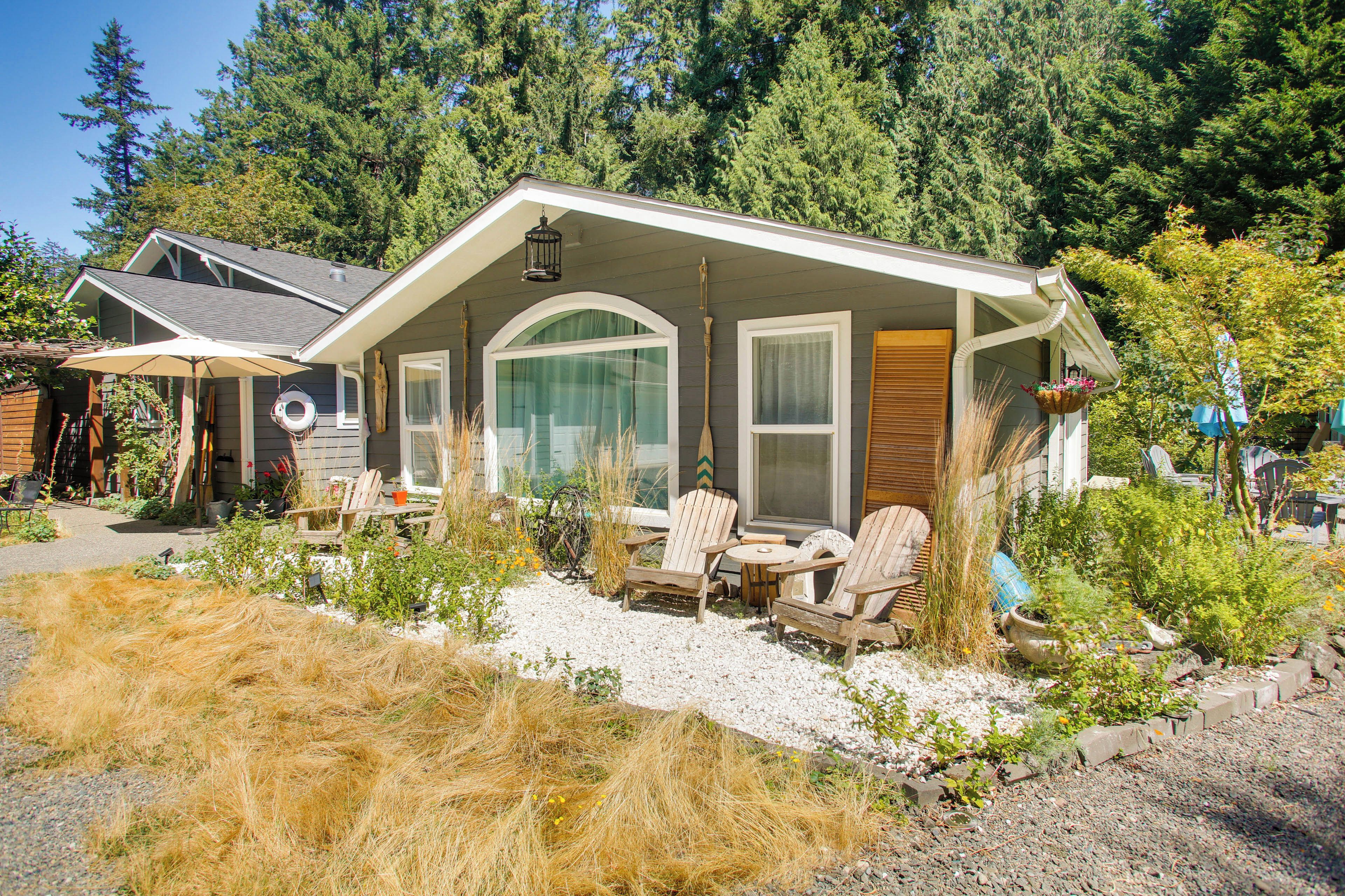 A house with a covered patio, outdoor seating, and a garden with various plants and a bicycle.