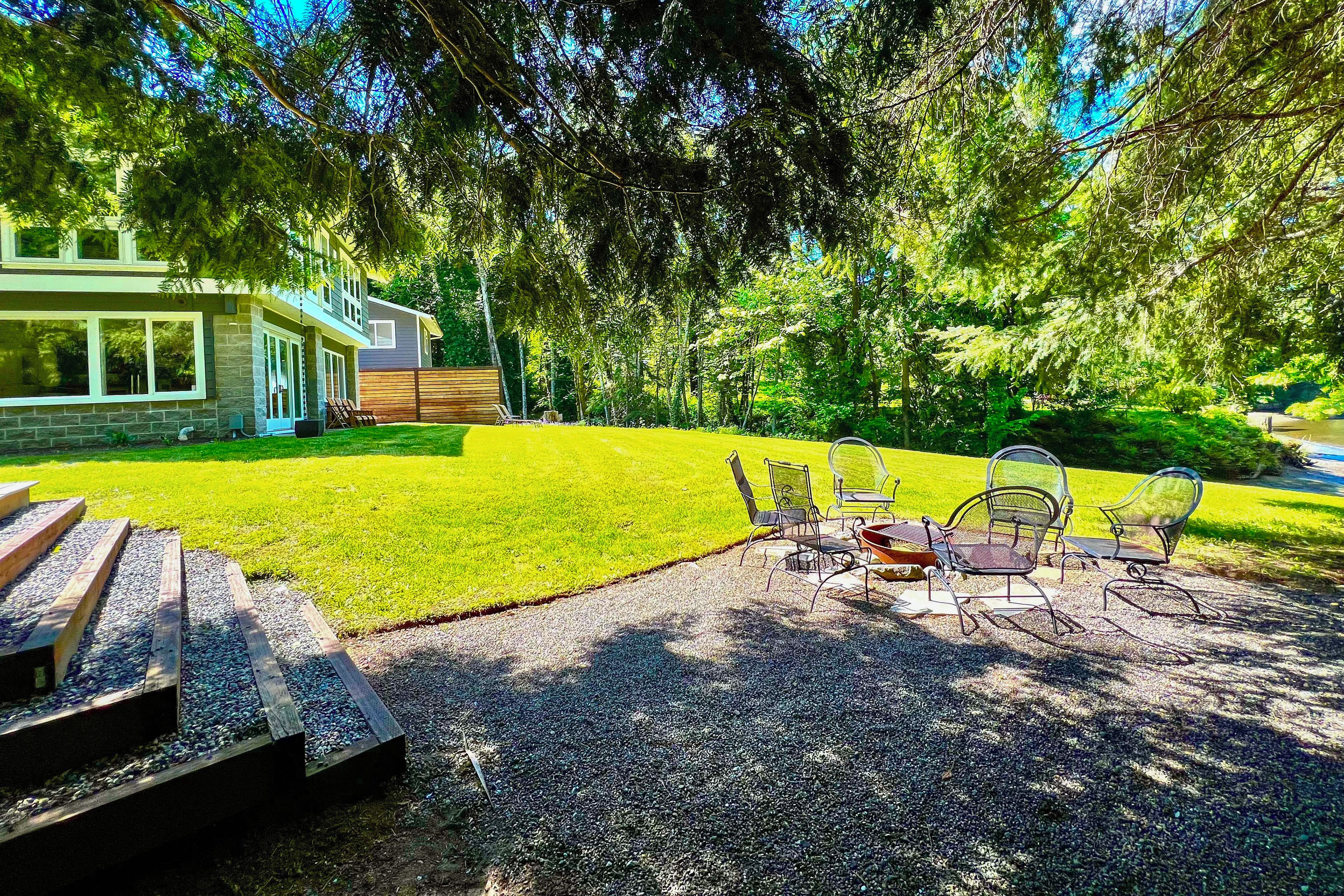 Een terras met tuinmeubilair, een vuurkorf en uitzicht op een huis met een stenen gevel.