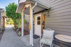 A house with a covered porch, a door, a small table, and a chair. - Bayfront PNW Lodge: Dock, Pickleball & Guest House (Bainbridge Island)