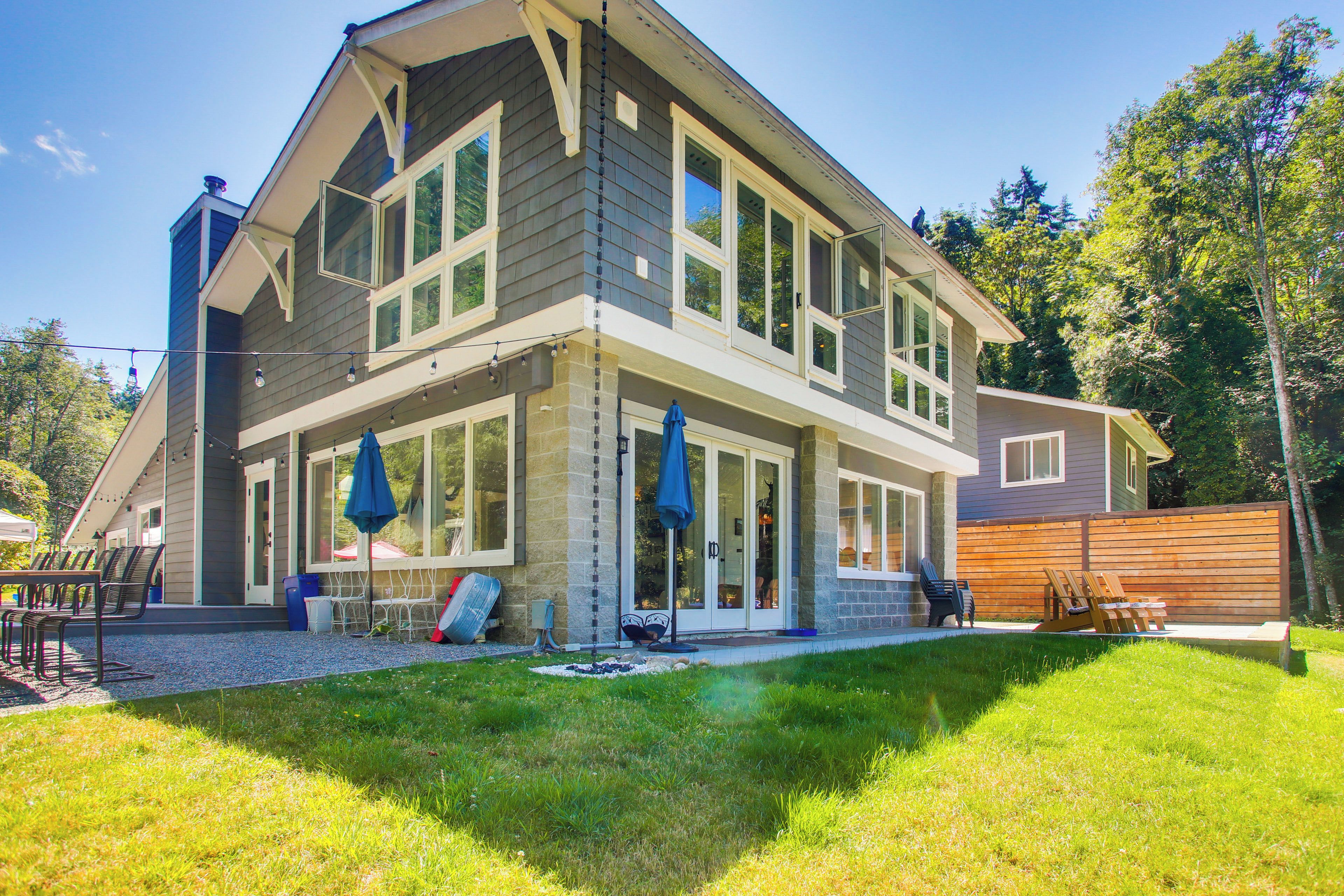 A two-story house with a covered patio area, a fenced backyard, and a well-maintained lawn.