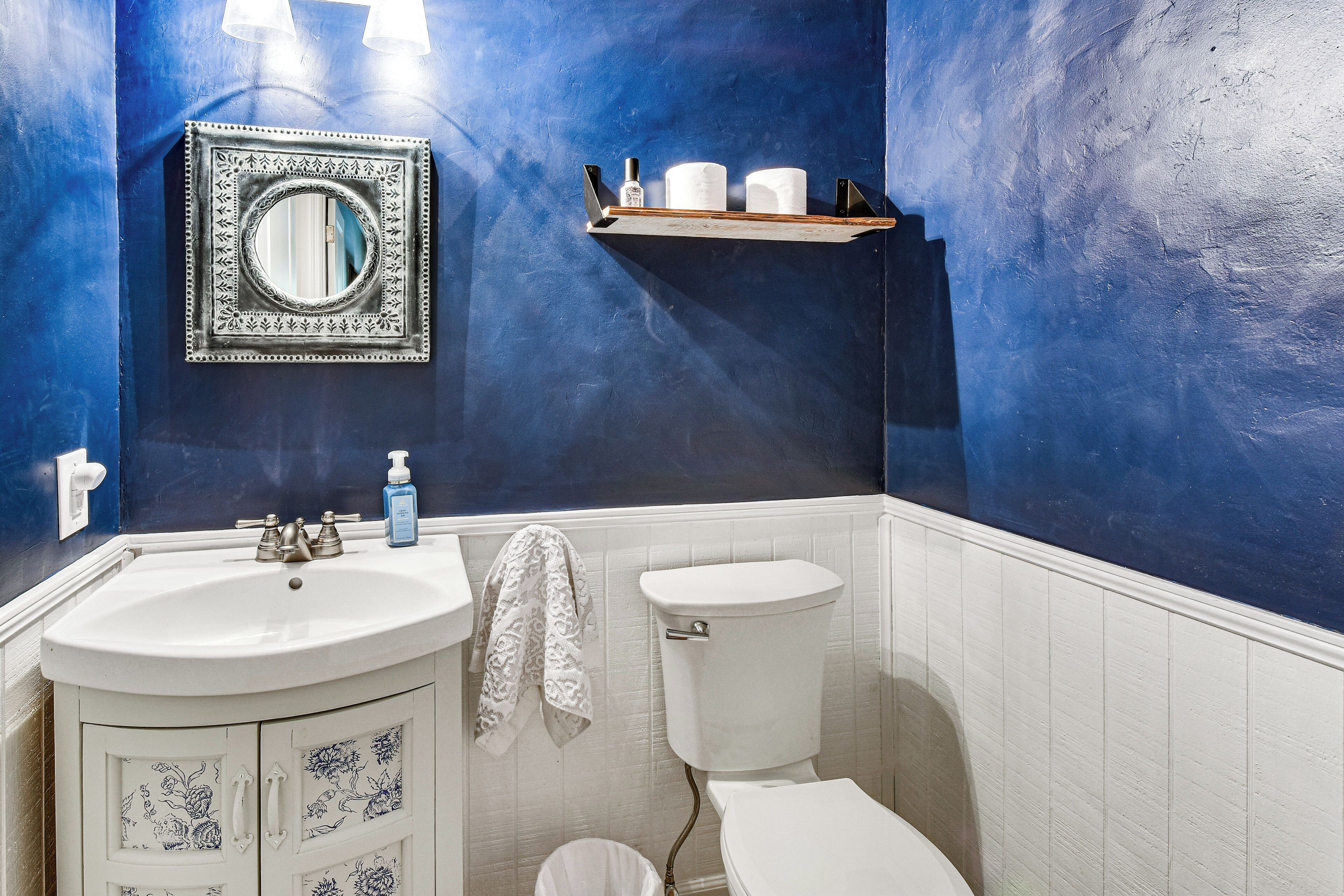 A bathroom with a white sink, a toilet, and a blue accent wall.