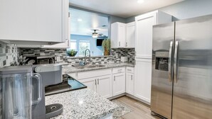 A modern kitchen with white cabinets, a stainless steel refrigerator, a coffee maker, and a window with a view of the outdoors. - Brownwood Family Home - 2 Mi to Public Marina! (Brownwood)
