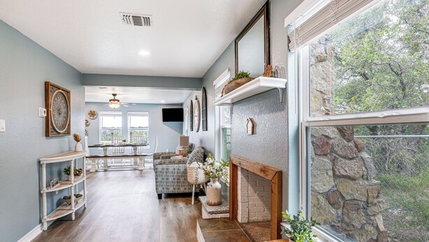 A spacious living area with a fireplace, a dining table, and a large window overlooking a stone wall. - Brownwood Family Home - 2 Mi to Public Marina! (Brownwood)