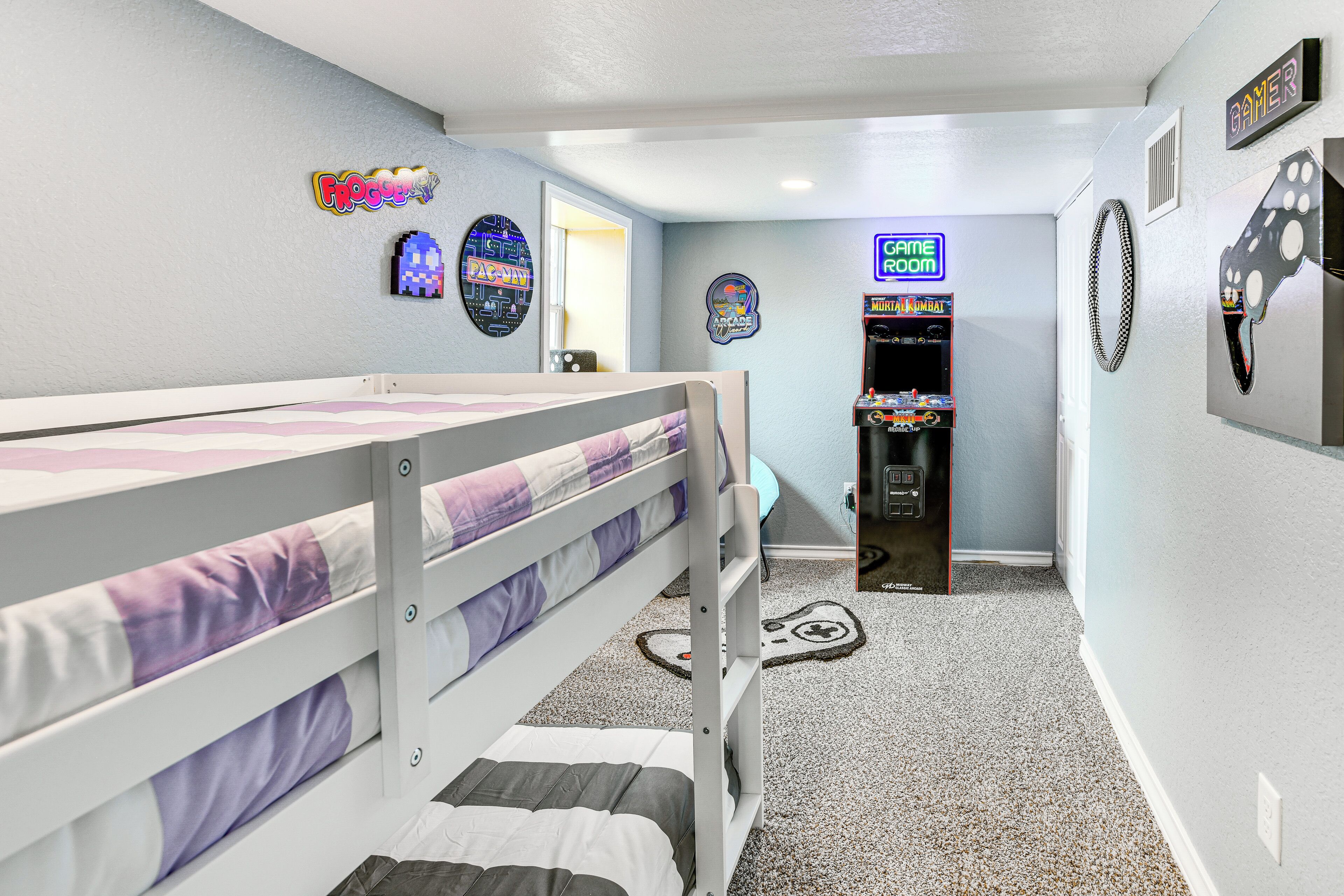 Un dormitorio con literas, una sala de juegos arcade y decoración de pared temática de arcade.