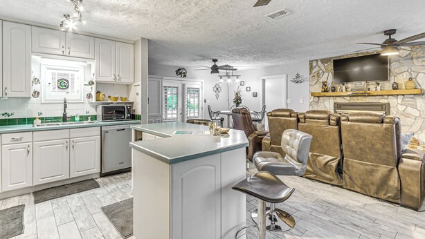 A modern kitchen with white cabinets, a central island, and a dining area with leather chairs. - Fort Walton Beach Home w/ Pool: 5 Mi to Beach! (Fort Walton Beach)