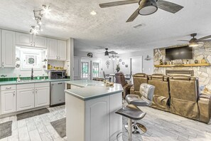 Une cuisine moderne avec des meubles blancs, un îlot central et un coin repas doté de chaises en cuir.
