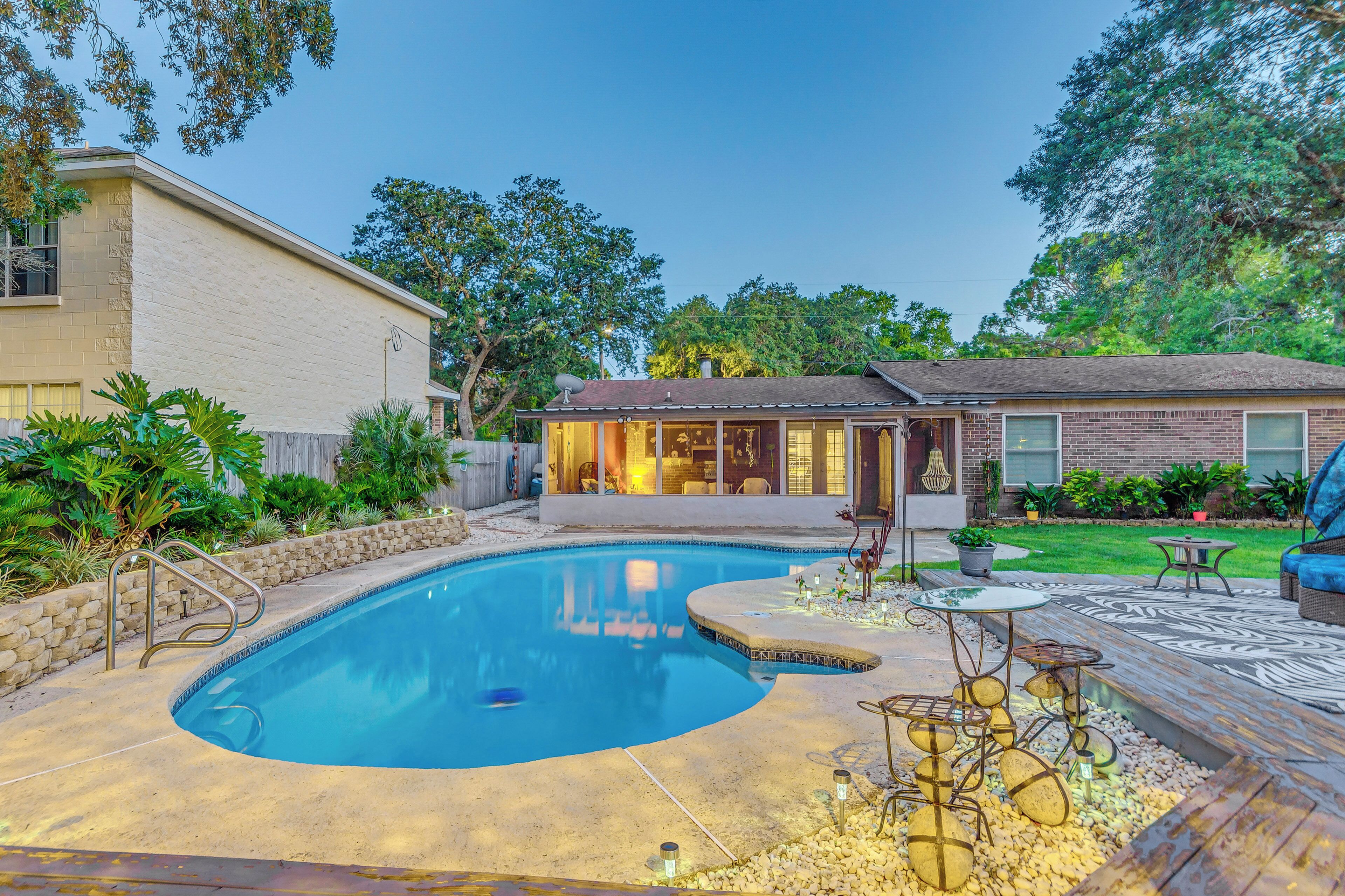 A backyard with a swimming pool, patio furniture, and a house.